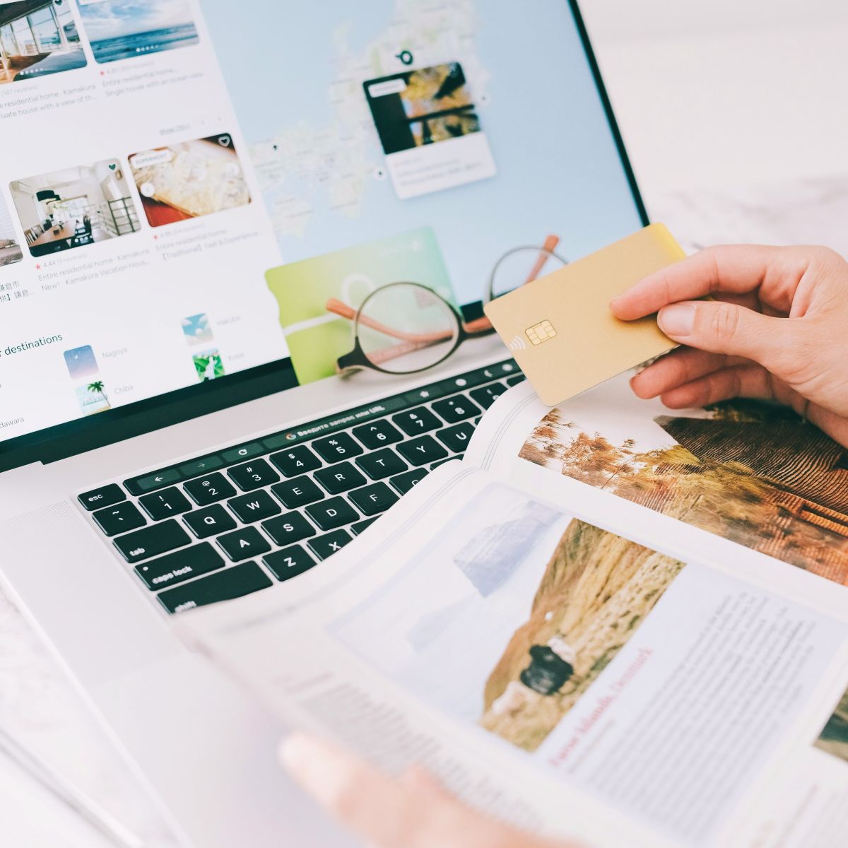 Computer open with tourism book and credit card in hand.