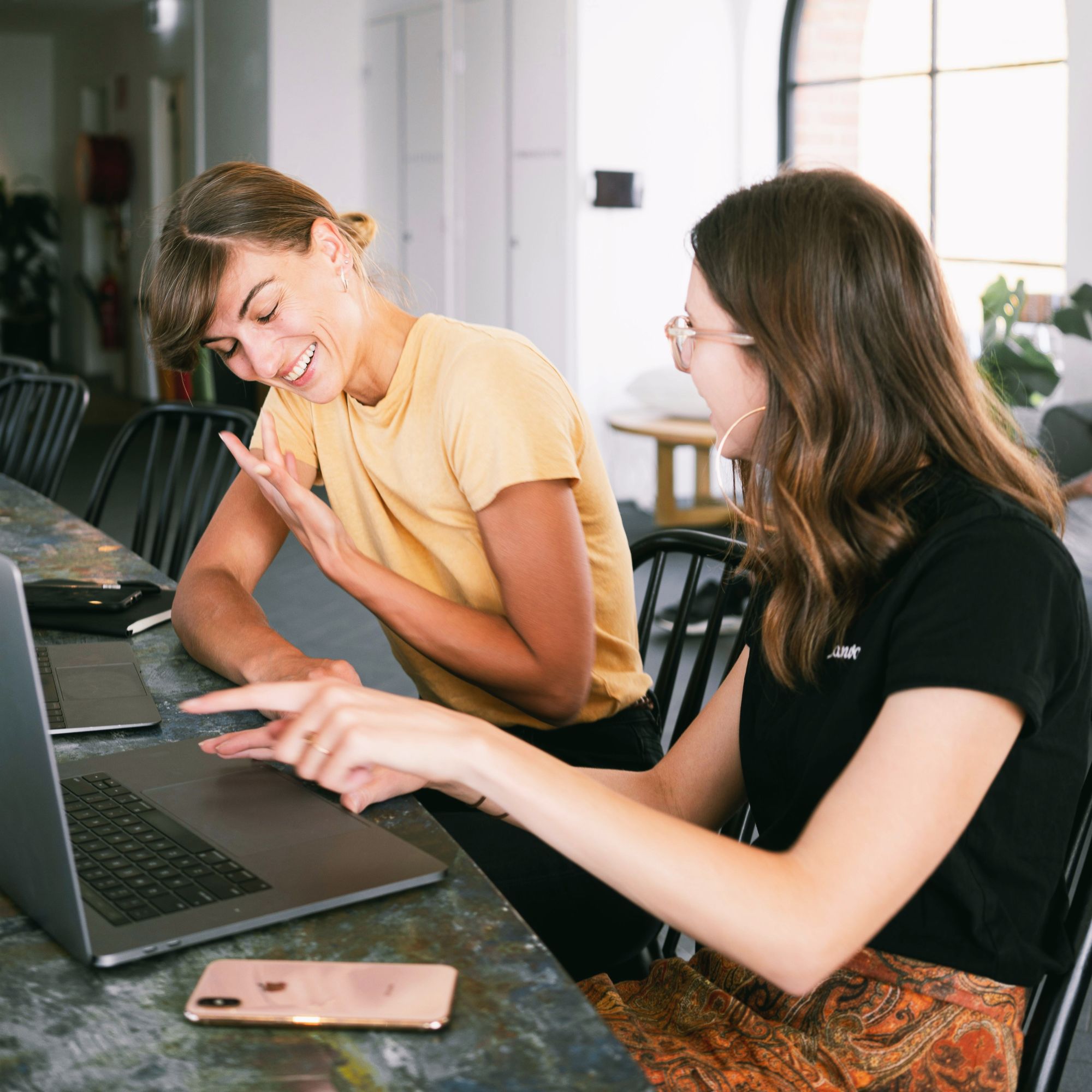 Two women talking and pointing at computer.