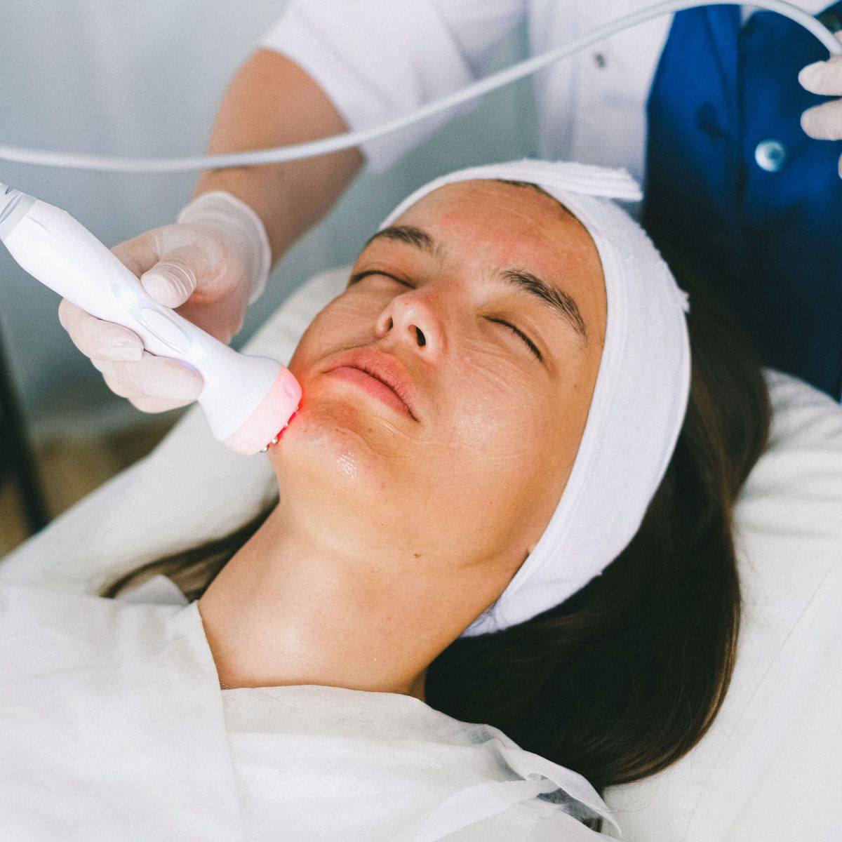 Woman receiving facial treatment in medical setting.