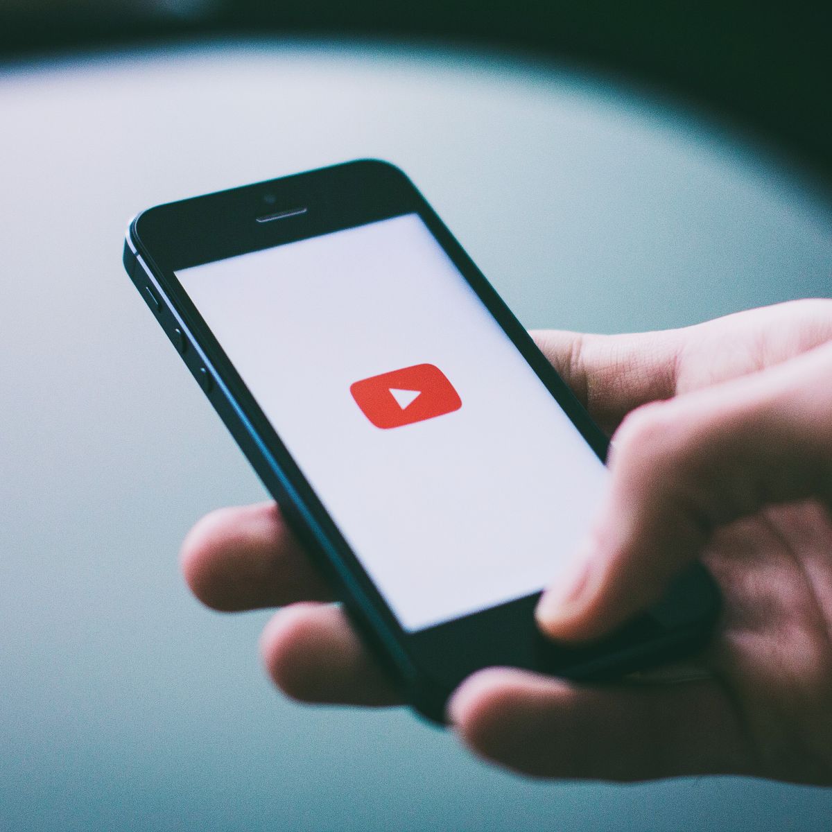 hand holding phone with youtube icon.