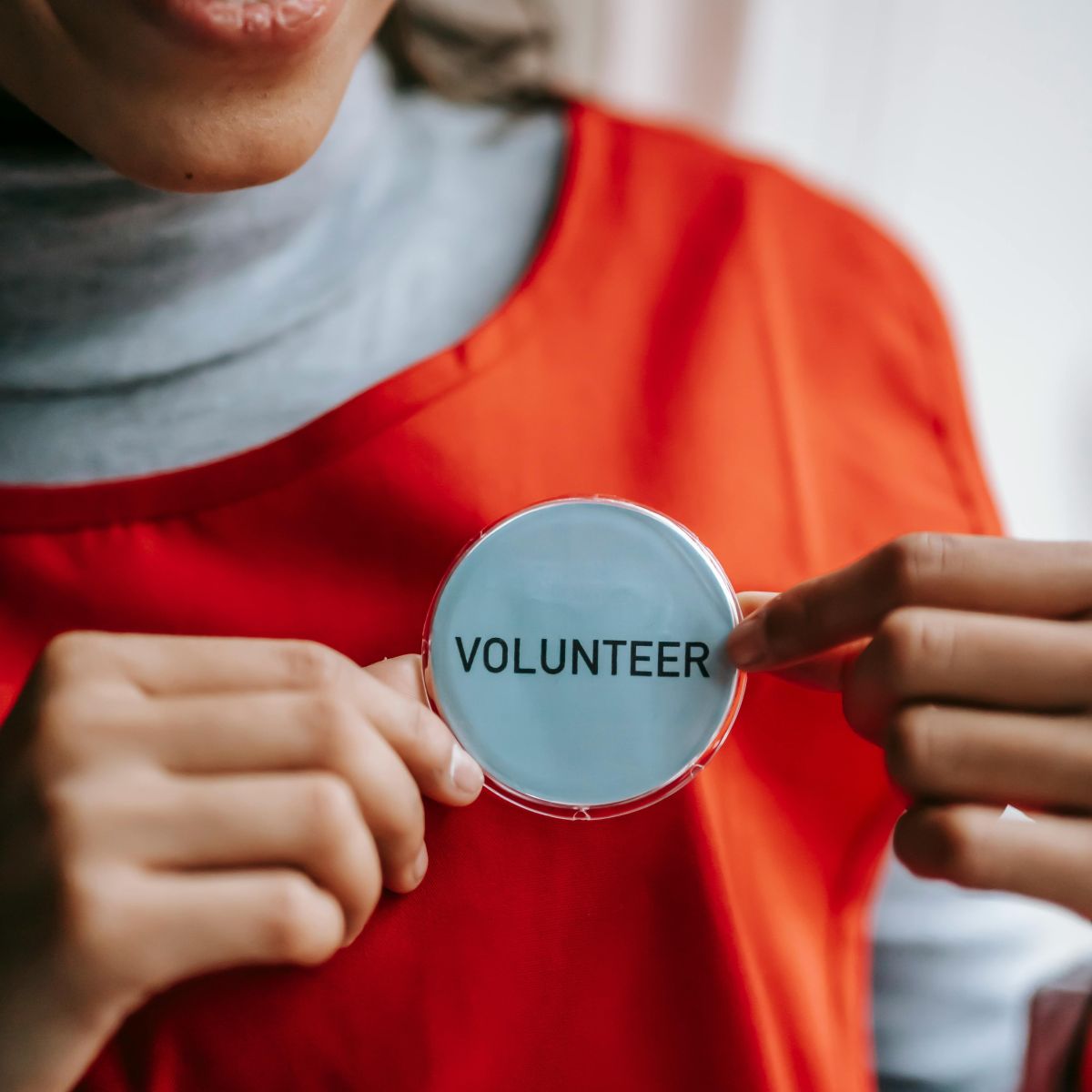 pexels-liza-summer-6348129_1200 Woman holding a name tag that reads volunteer.